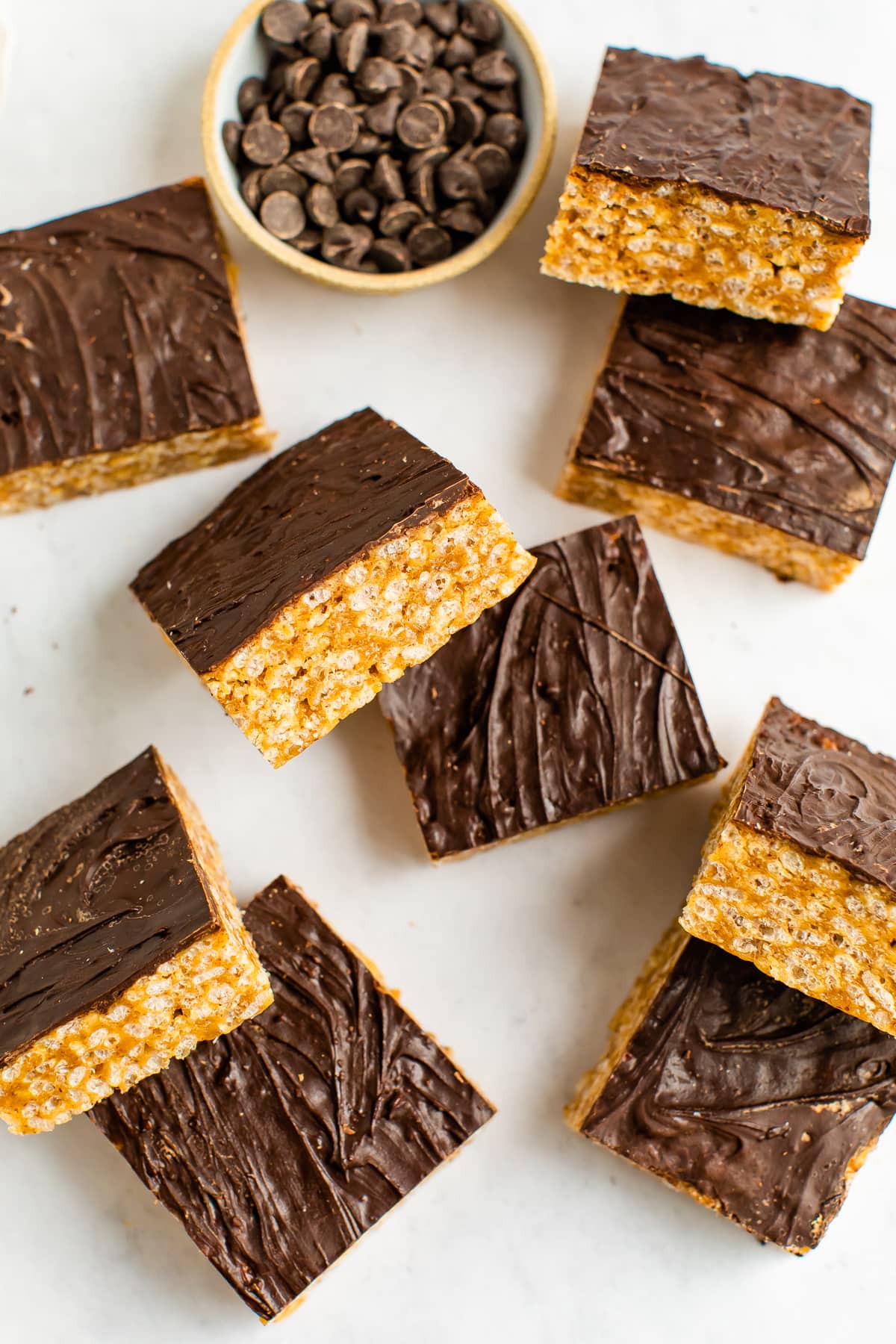 Chocolate topped rice krispie treats on a white table top.