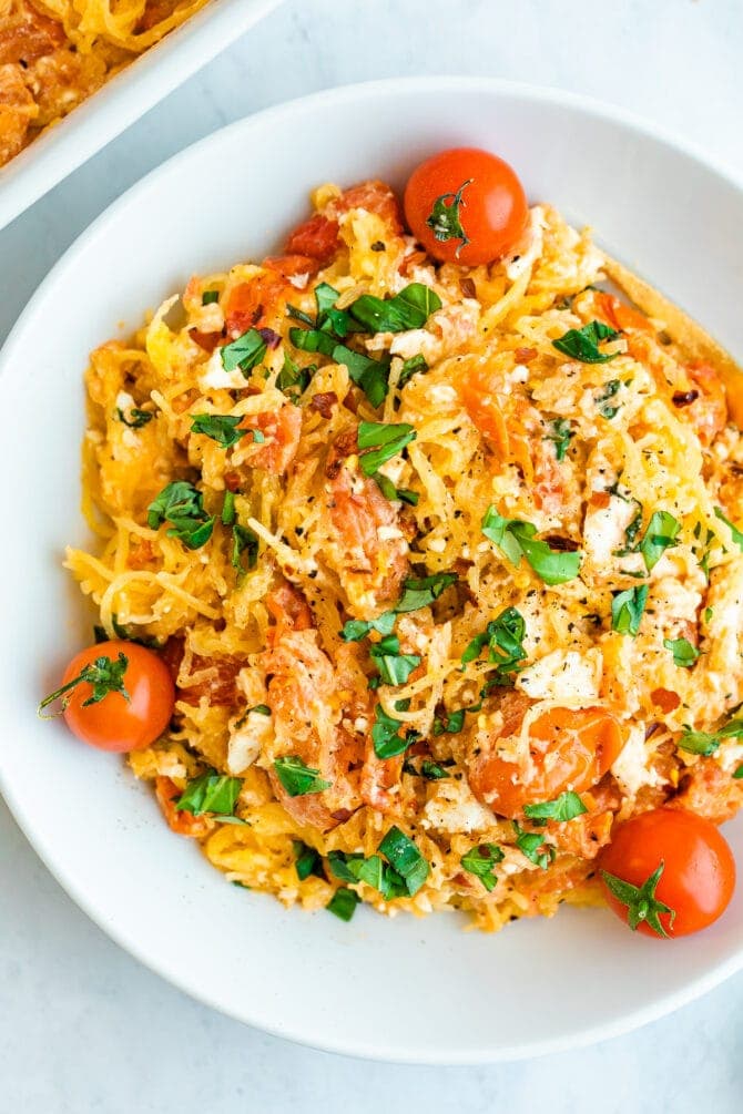 Plate of spaghetti squash with feta, basil and tomatoes.