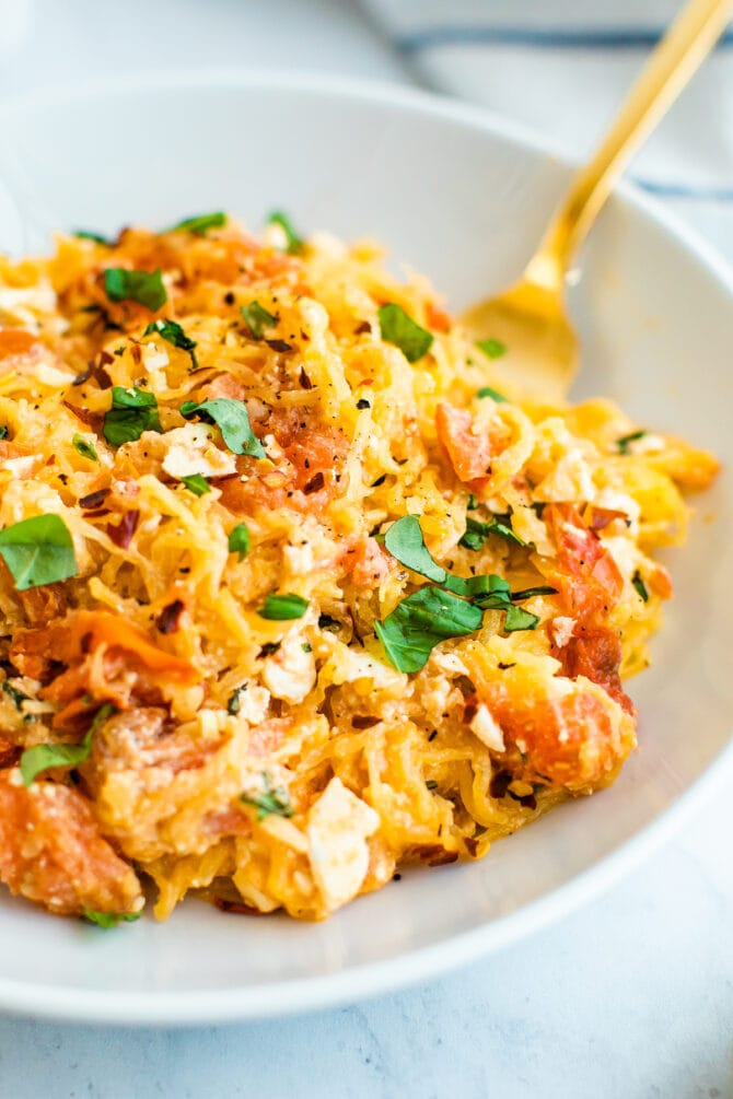 Plate of spaghetti squash with feta, basil and tomatoes.