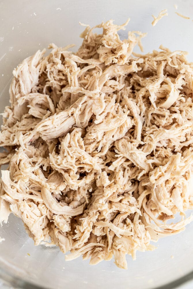 Chicken breasts that have been shredded in a bowl.