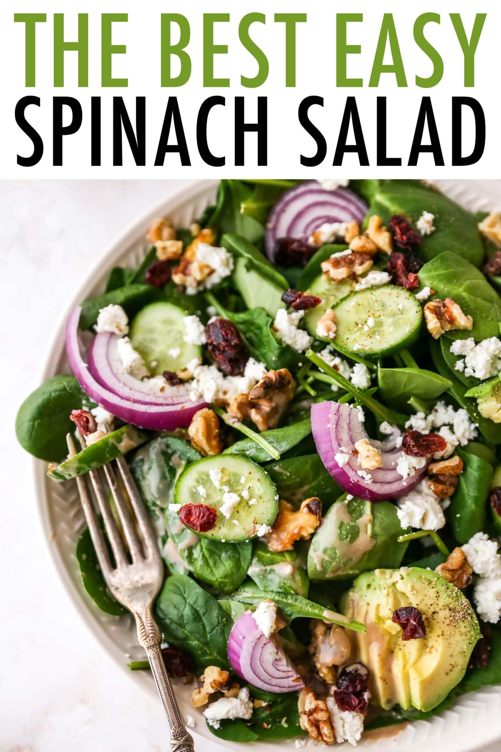 Plated spinach salad topped with avocado, goat cheese, cranberries, walnuts, onion and a drizzle of creamy balsamic dressing.
