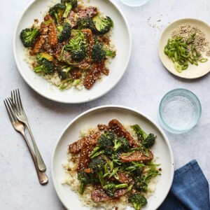 Two plates of teriyaki tempeh and broccoli served over rice.