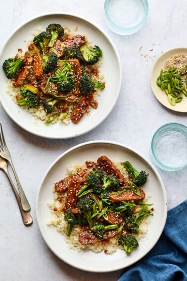 Two plates of teriyaki tempeh and broccoli served over rice.