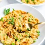 Fork taking a bite from a dish of spaghetti squash noddles with a creamy walnut sauce.