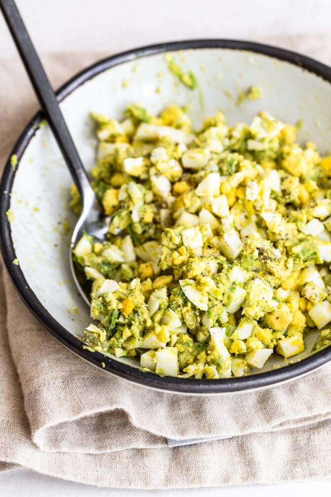 Bowl with avocado egg salad and spoon.