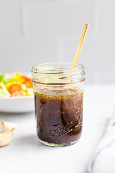 Mason jar with balsamic dressing and a spoon in the jar.