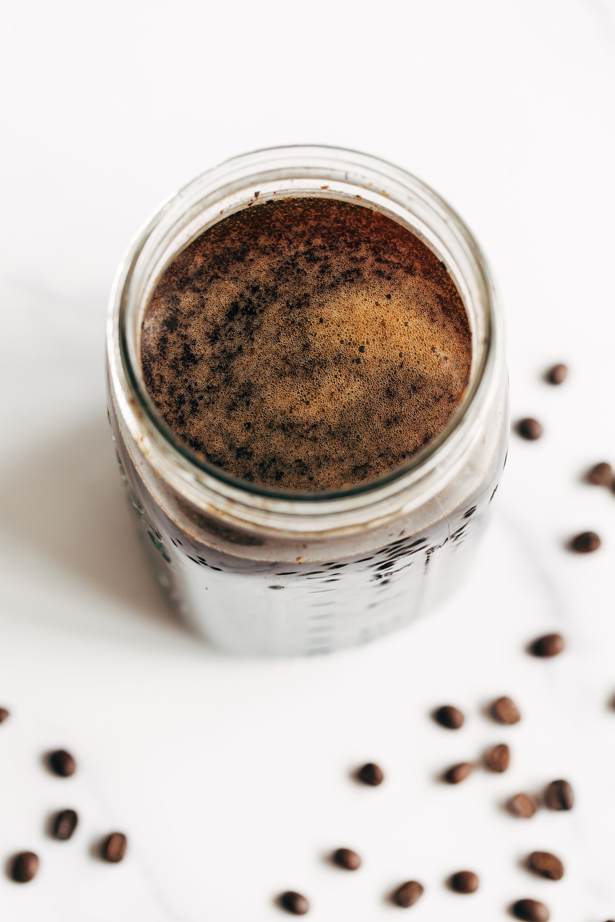 Cold brew in a mason jar. Coffee beans are around the jar.