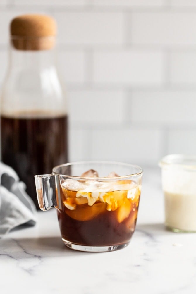 Glass jar with cold brew and cream mixing into the coffee.