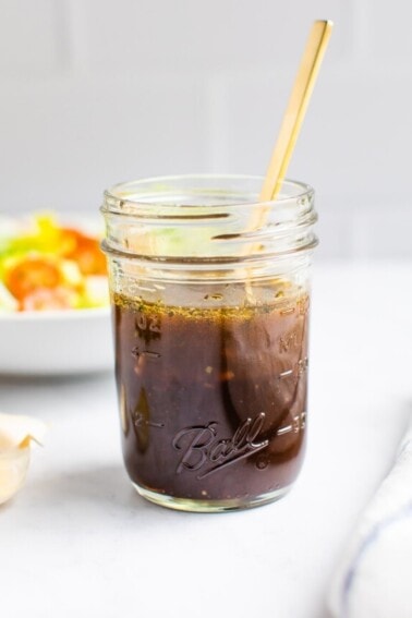 Mason jar with balsamic dressing and a spoon in the jar.