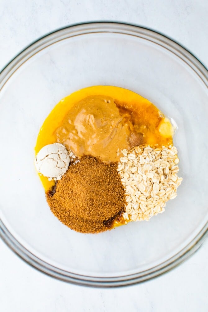 Mixing bowl with egg, peanut butter, oats, coconut sugar and oat flour.