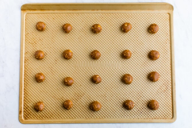 Cookie sheet with balls of peanut butter cookie dough.