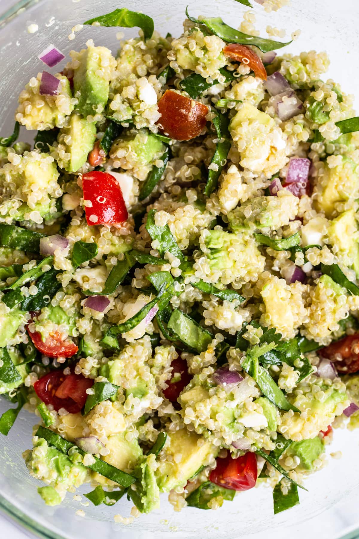 Bowl of quinoa salad with feta, spinach and tomatoes.
