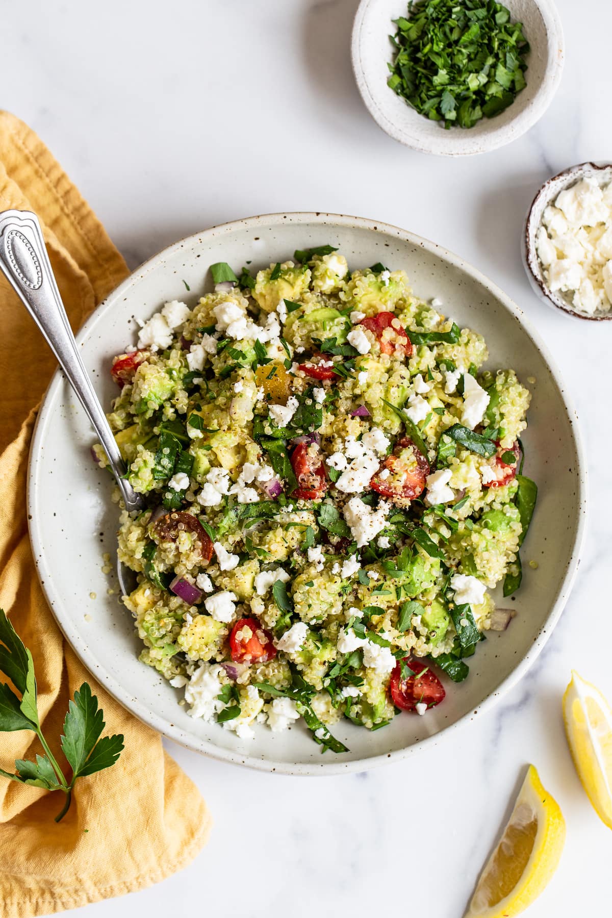 Bowl of quinoa salad with feta, spinach and tomatoes.