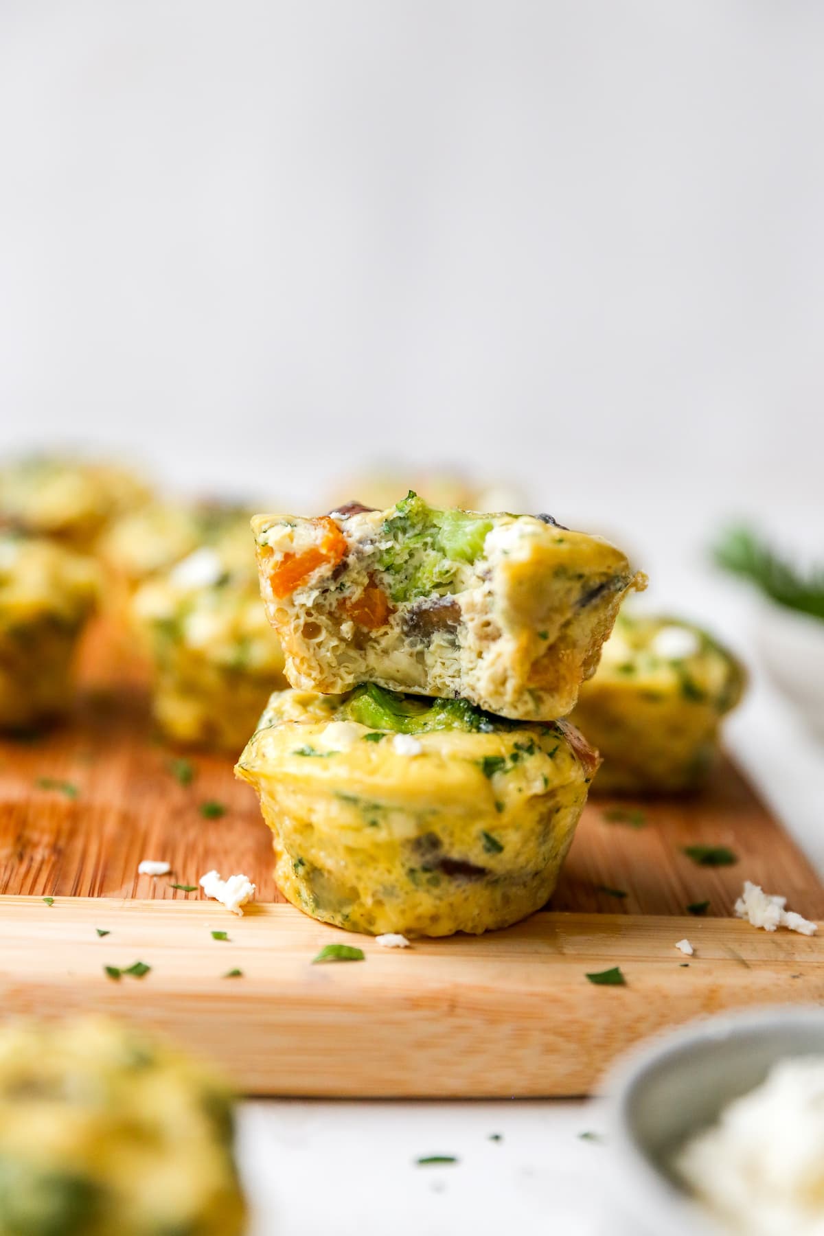 Two stacked egg muffins with veggies. The top egg cup has a bite taken out of it.