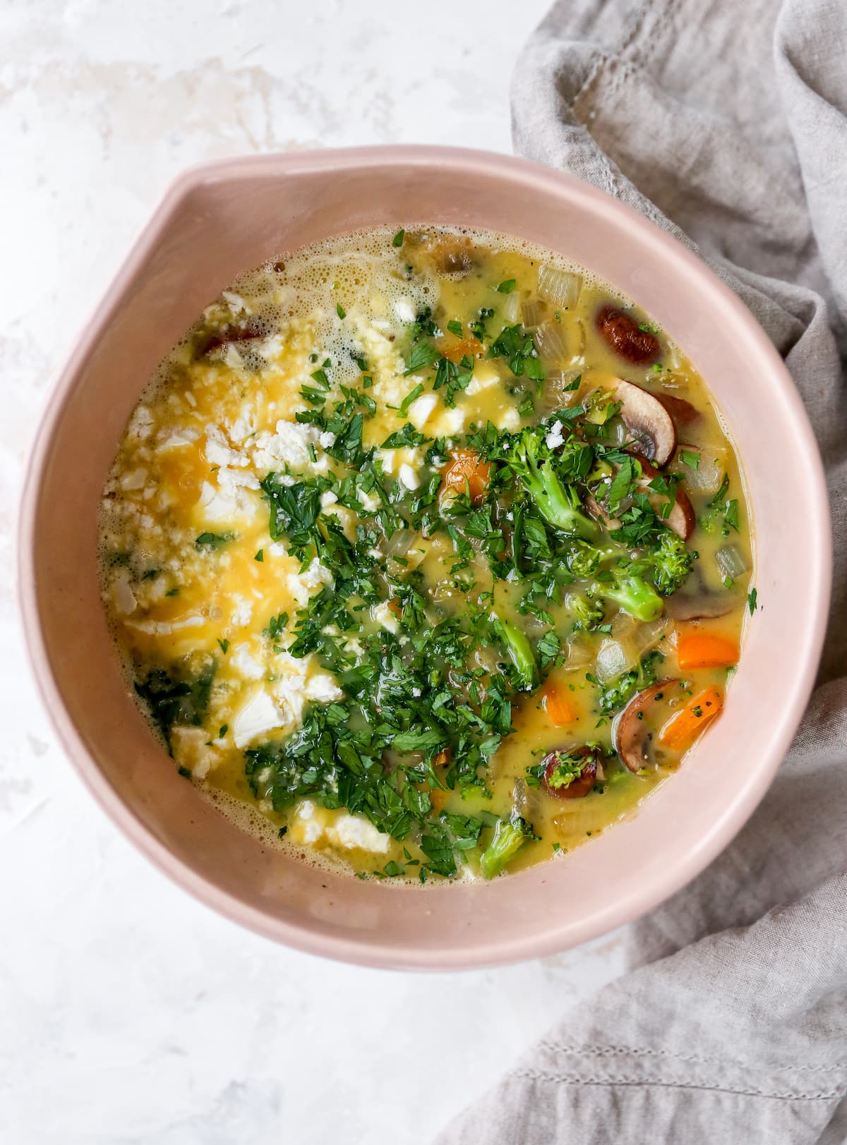 Mixing bowl with veggies, egg and cheese.