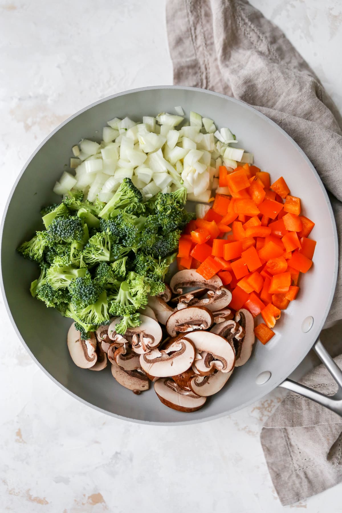 Skillet with onion, pepper, mushroom and broccoli uncooked.