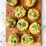 Baked egg and veggie cups on a wood cutting board.