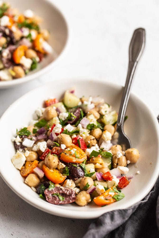 Small bowl with a fork and Greek chickpea salad.