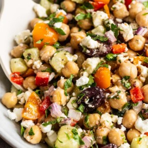 Greek chickpea salad in a bowl with a serving spoon.