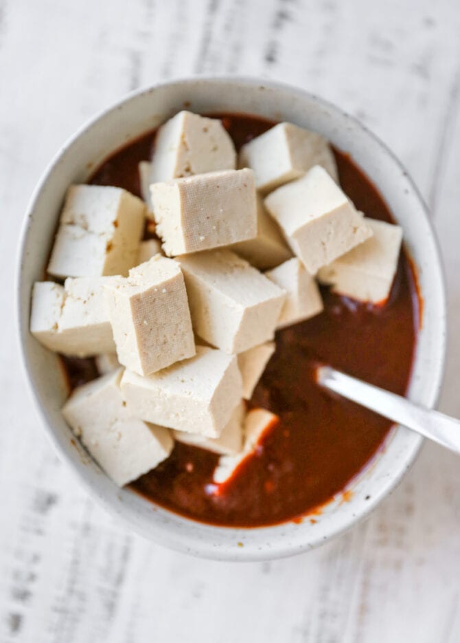 Cubes of tofu in a bowl of kung pao marinade.
