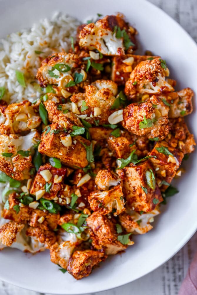 Kung pao tofu and cauliflower served over rice and topped with cilantro, green onion and peanuts.