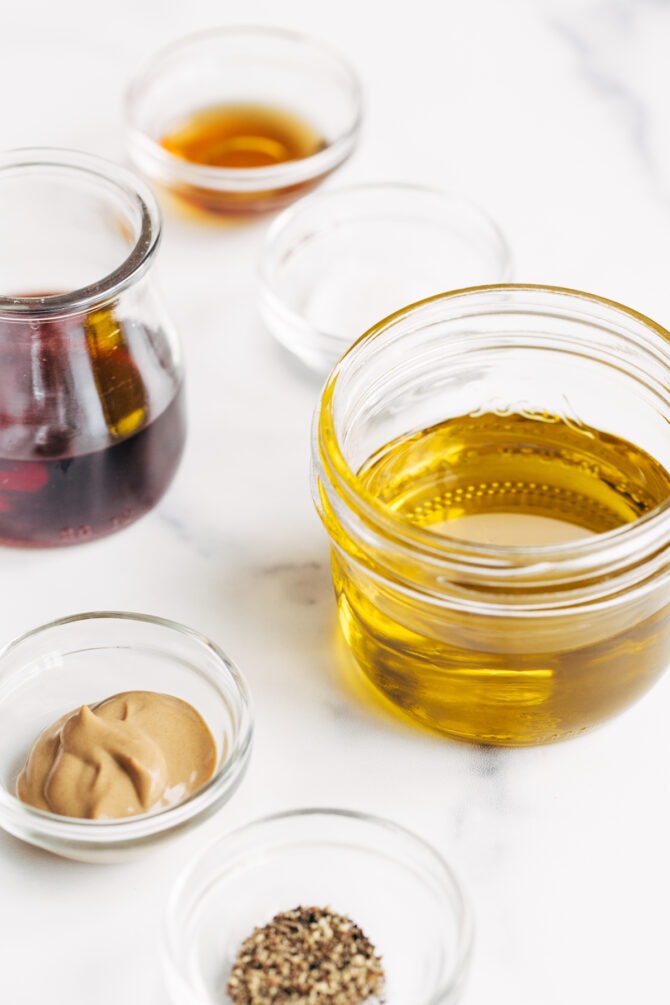 Ingredients to make red wine vinaigrette measured out in bowls and jars.