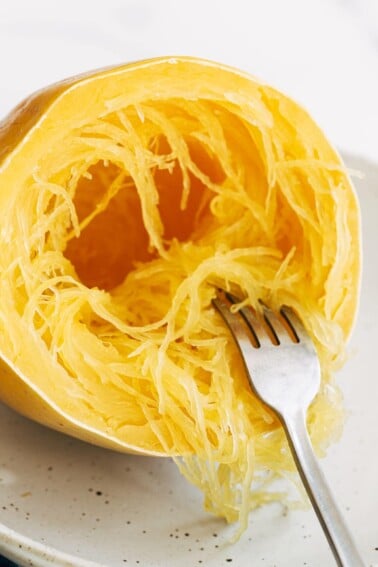 Fork pulling apart strands of spaghetti squash.