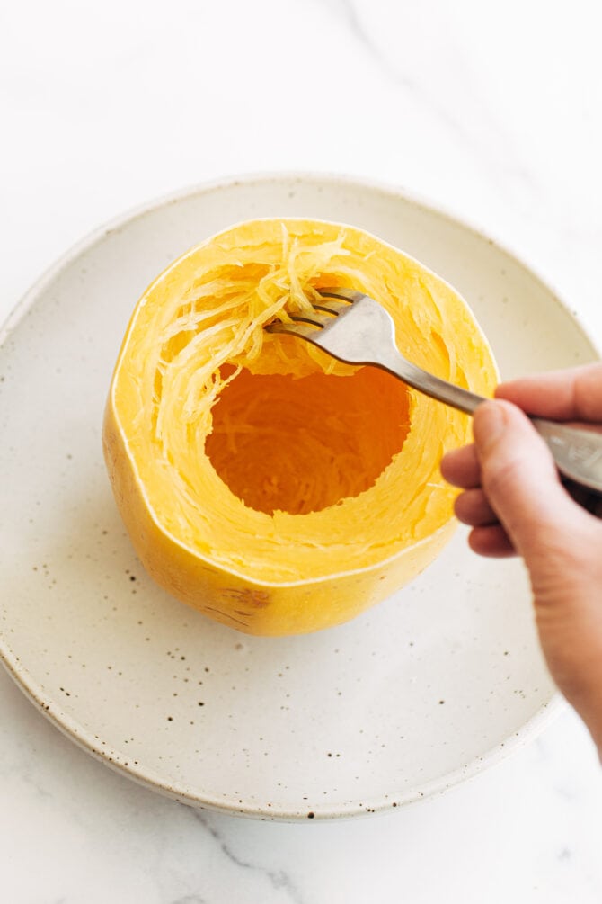 Fork pulling apart strands of spaghetti squash.