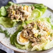 Two tuna egg salad lettuce wraps on a plate.
