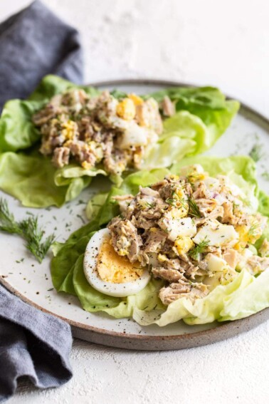 Two tuna egg salad lettuce wraps on a plate.