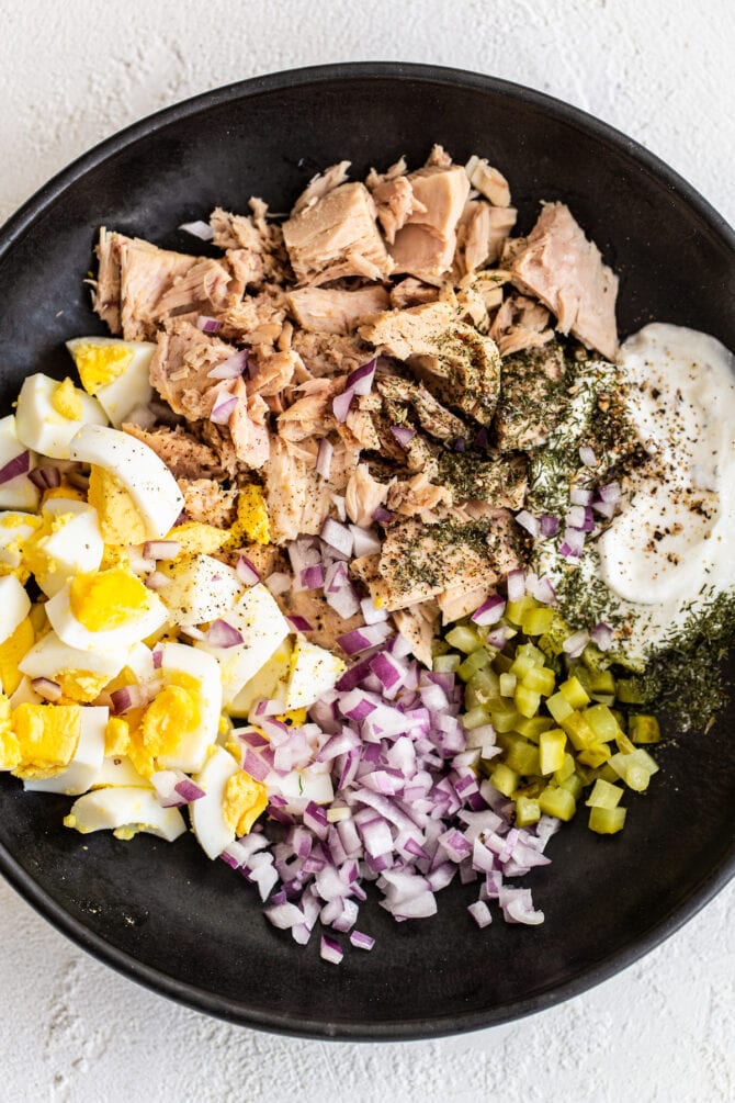 Bowl with hard boiled eggs, onion, pickles, spices, Greek yogurt and tuna.