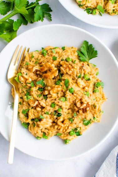 Plate of spaghetti squash noodles with a creamy walnut sauce and topped with walnuts and parsley.