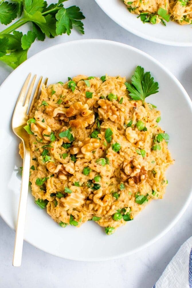 Plate of spaghetti squash noodles with a creamy walnut sauce and topped with walnuts and parsley.