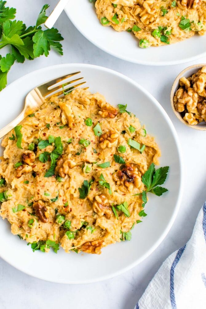 Plate of spaghetti squash noodles with a creamy walnut sauce and topped with walnuts and parsley.