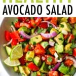 Serving bowl with avocado and tomato salad garnished with lime and cilantro.