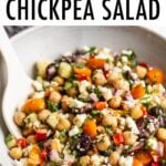 Greek chickpea salad in a bowl with a serving spoon.