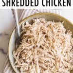 Bowl of shredded chicken with a fork.