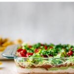 Side view of a glass dish of Mexican layer dip so you can see the layers.