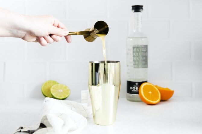 Pouring orange juice into a cocktail shaker.