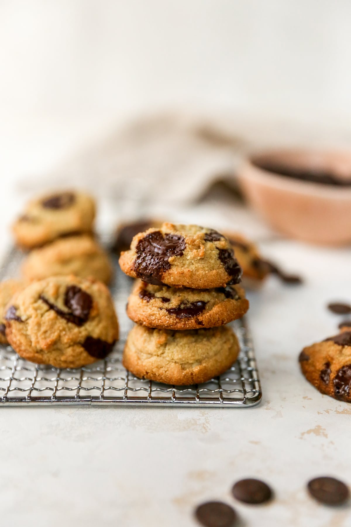 Stack of three chocolate chip cookies on a wire cooling rack.