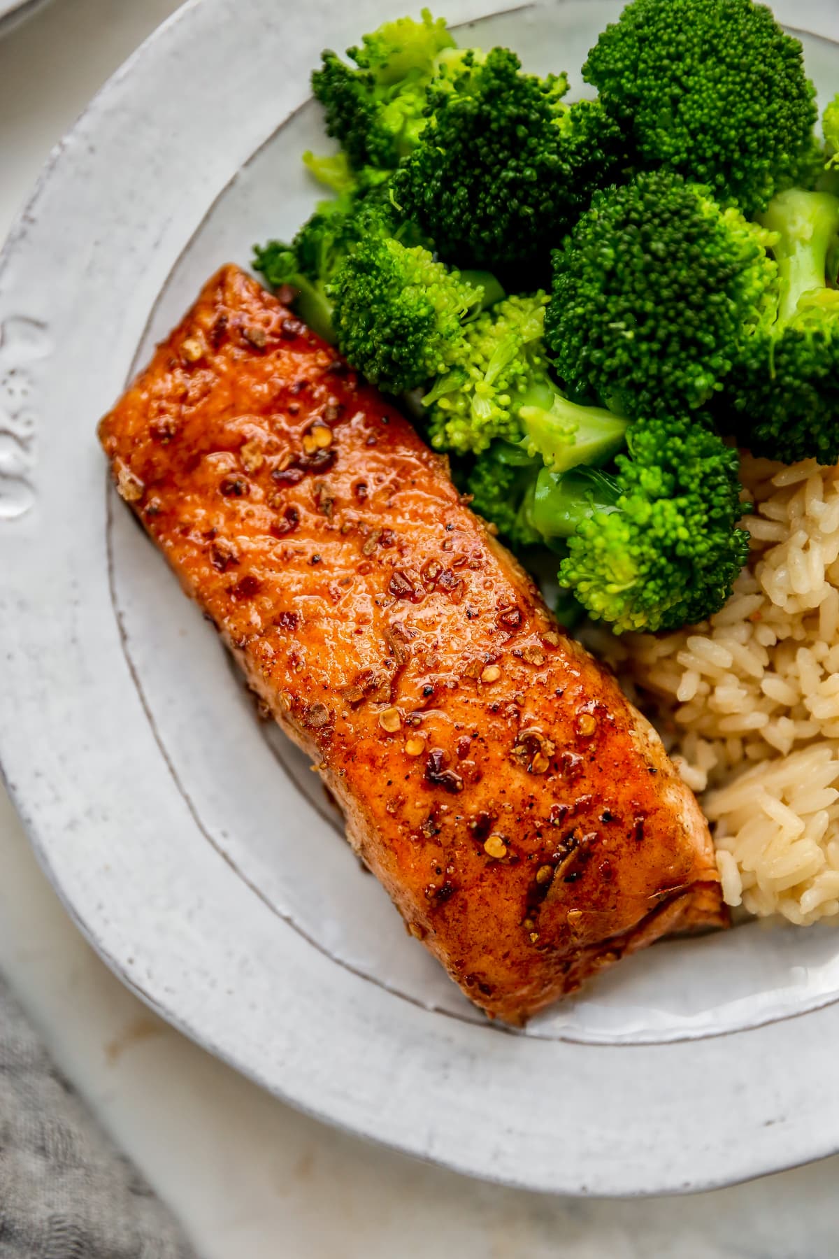 Plate with a piece of balsamic salmon, brown rice and broccoli.