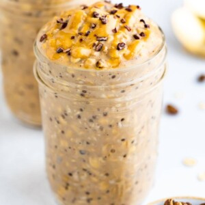 Two jars of coffee overnight oats topped with peanut butter and cocoa nibs.