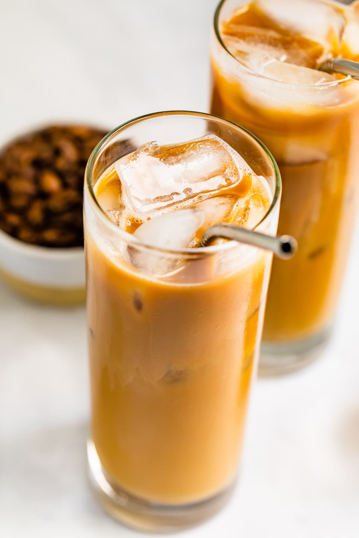 Glass of cold brew and cream with a metal straw in the glass.