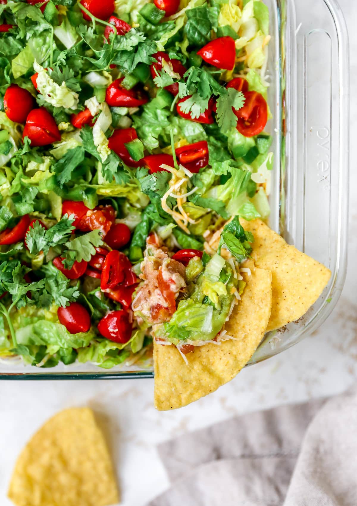 Tortilla chips in a dish of Mexican layer dip.