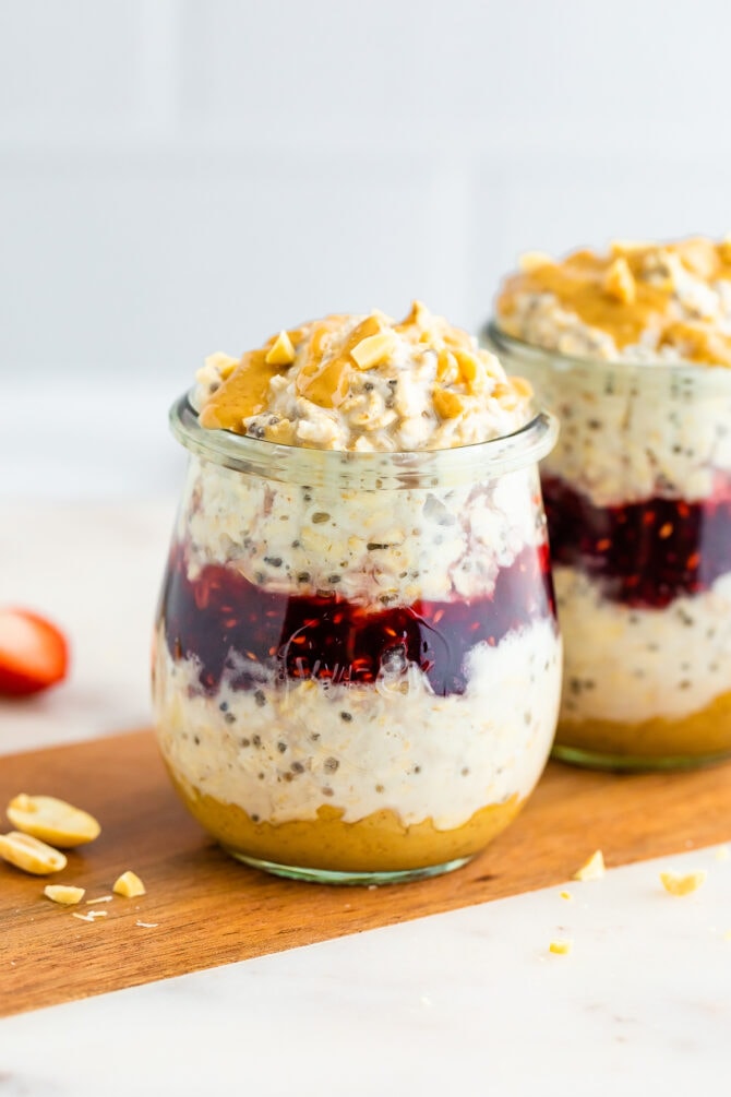 Two jars of peanut butter overnight oats layered with peanut butter and jelly.