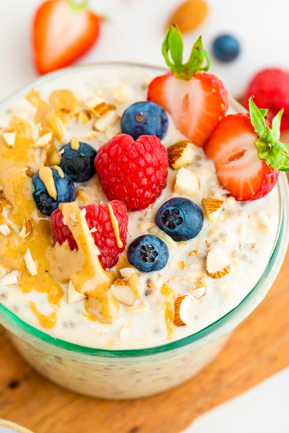 Jar of protein overnight oats topped with berries, almonds and peanut butter.