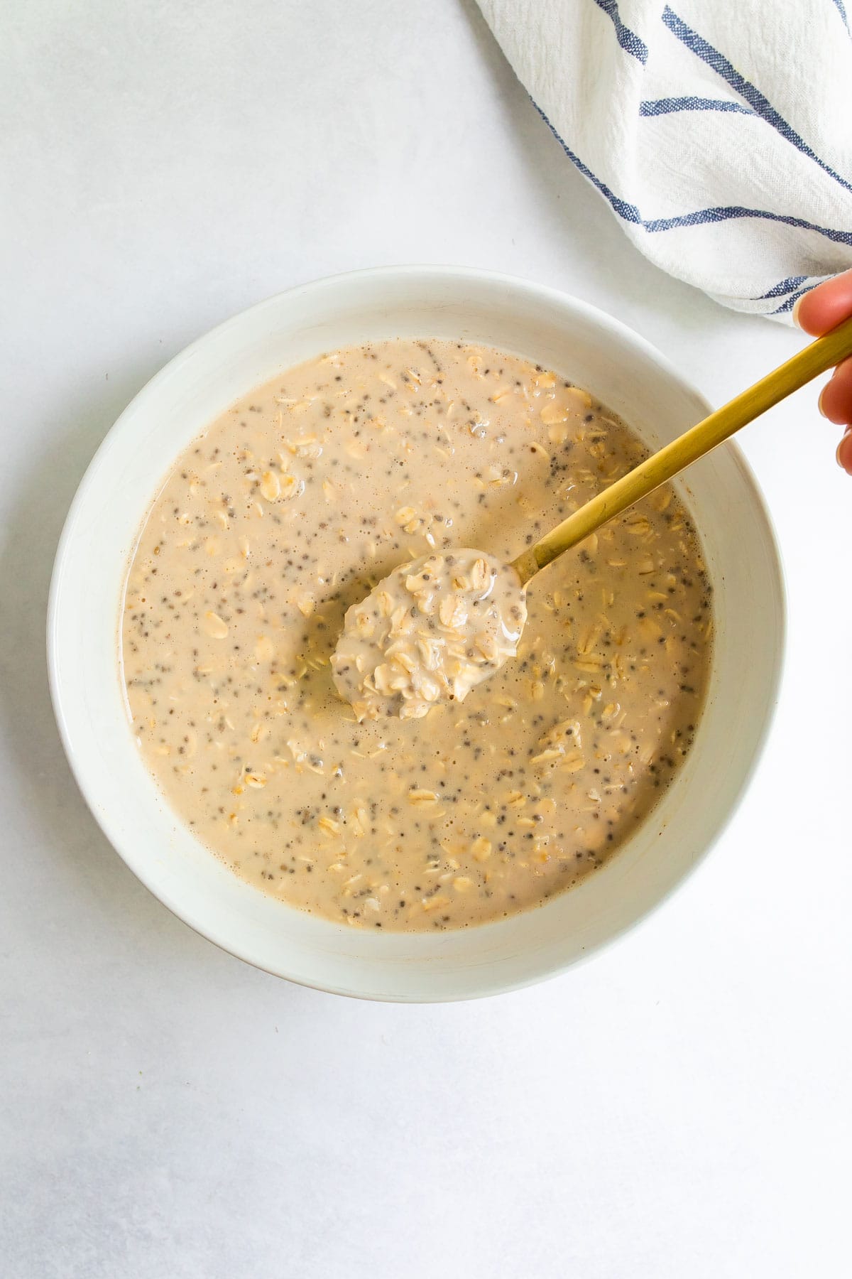 Spoon with a spoonful of protein overnight oats from a bowl.