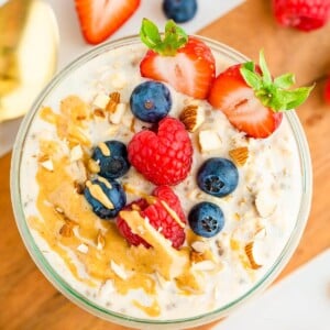 Jar of protein overnight oats topped with berries, almonds and peanut butter.