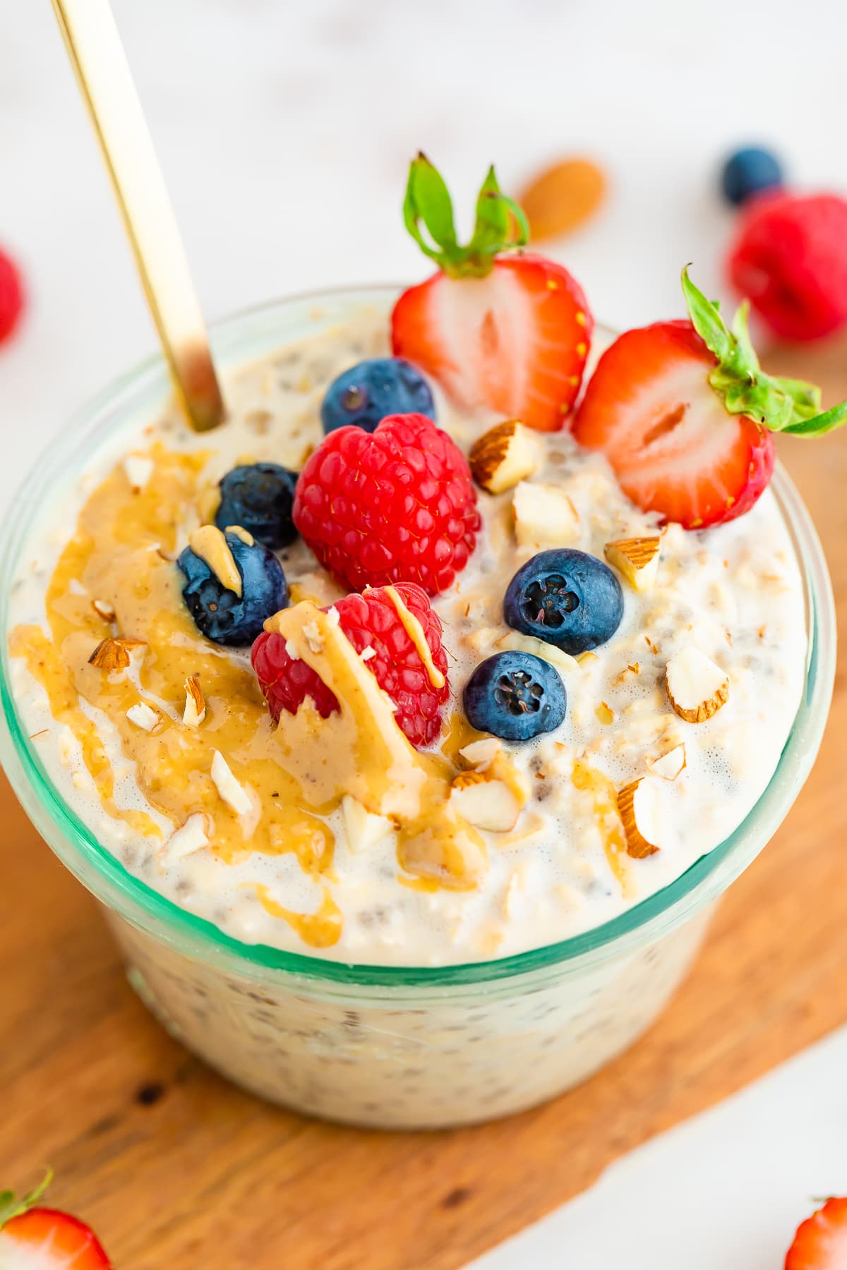 Jar of protein overnight oats topped with berries, almonds and peanut butter.