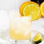 Glass of a skinny margarita with slices of lime and orange.